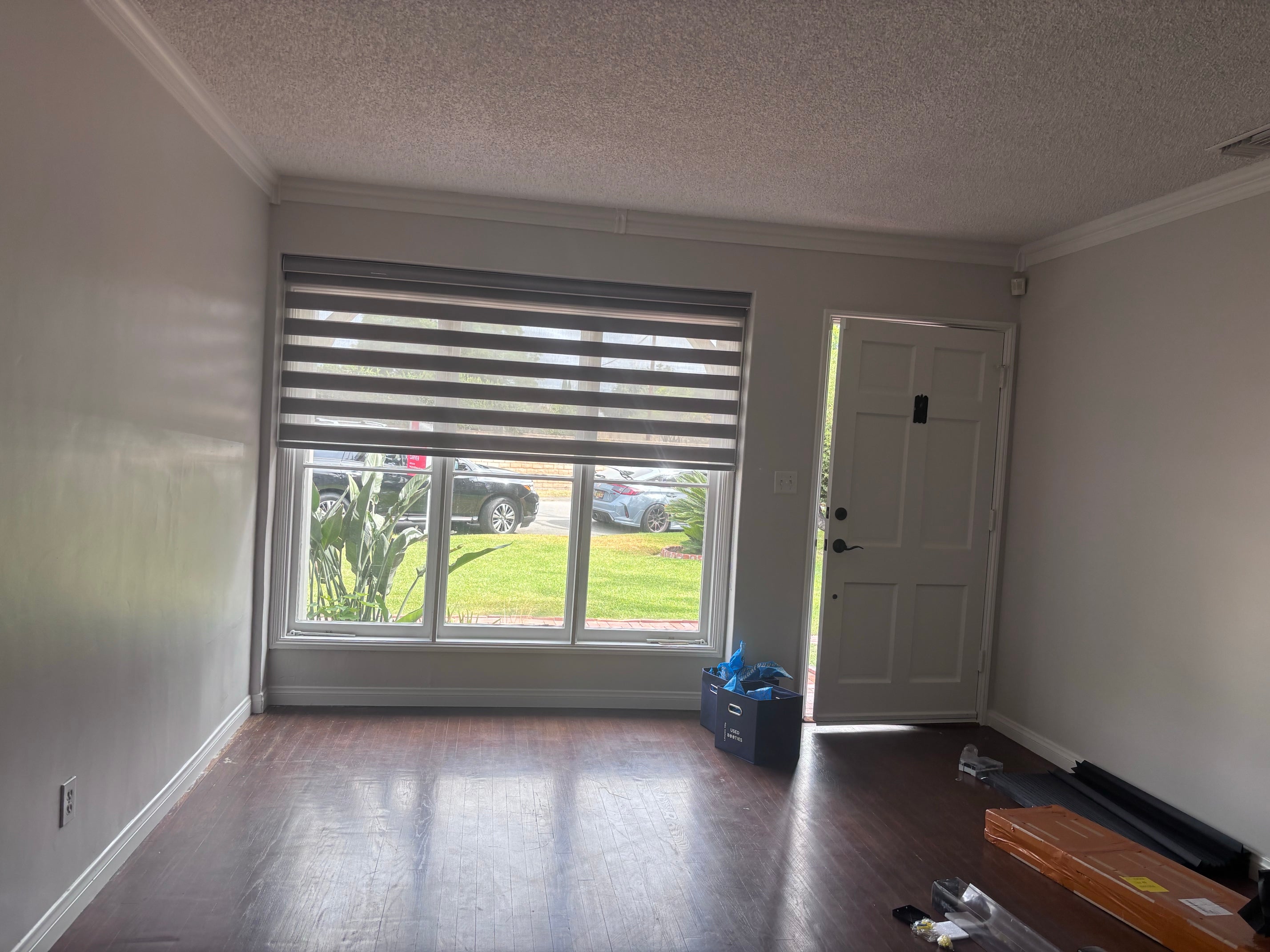 White zebra shades with alternating sheer and solid fabric bands covering a large residential window.